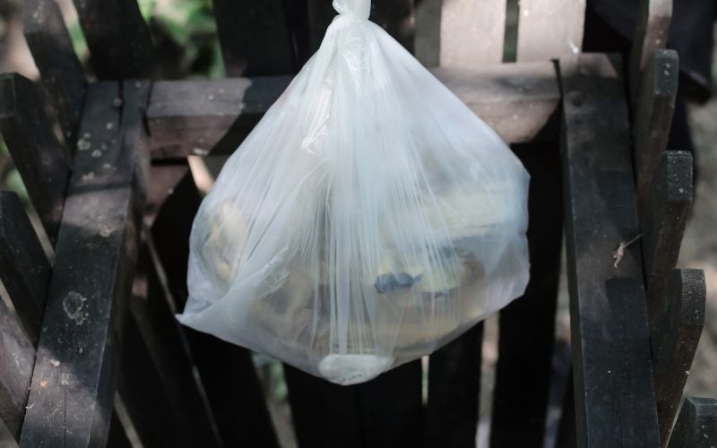 A white plastic trash bag to be thrown in a bin.