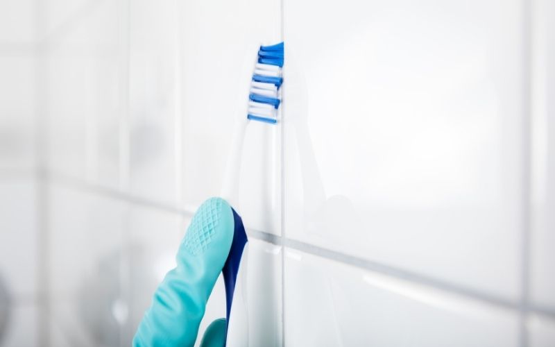 a tile being cleaned using a toothbrush with white vinegar