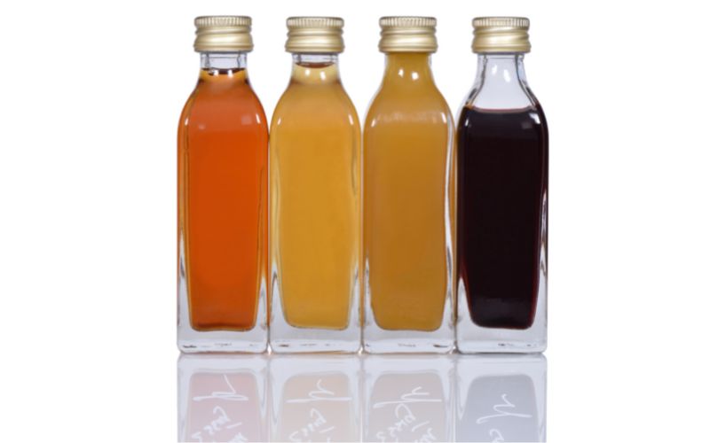 Four clear bottles of different kinds of vinegars