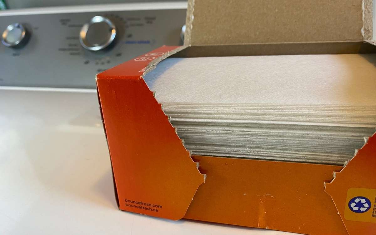 Folded laundry dryer sheet in brown box on a washing machine