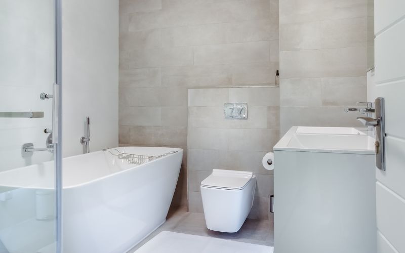 A clean bathroom showing white bath tub, a toilet and sink.