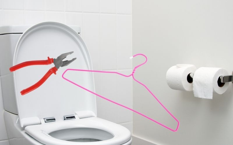 A pink hanger and a plier over a toilet bowl to unclog it
