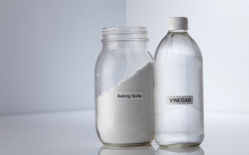 A jar of baking soda and a bottle of white vinegar