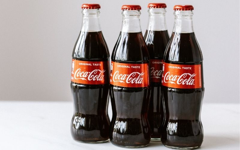 Four bottles of coca cola on white table