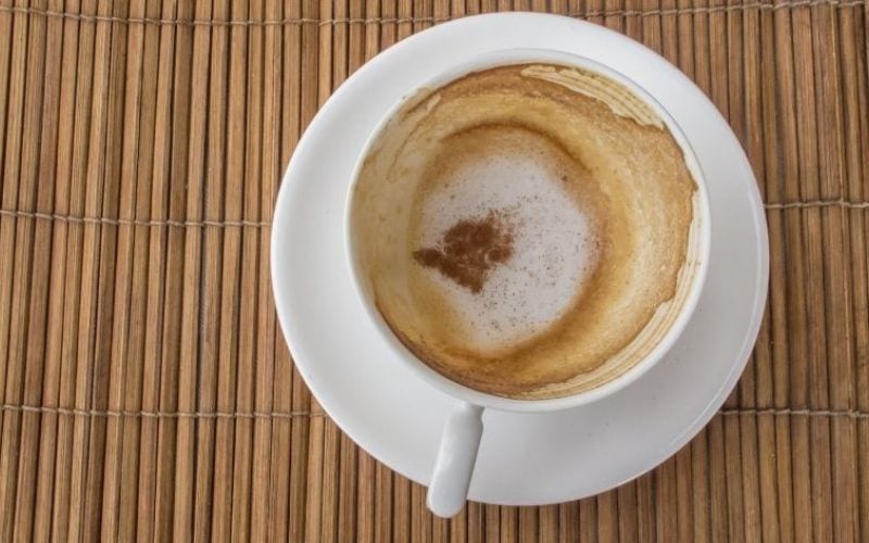 A coffee cup with stain on white saucer that can be cleaned using baking soda