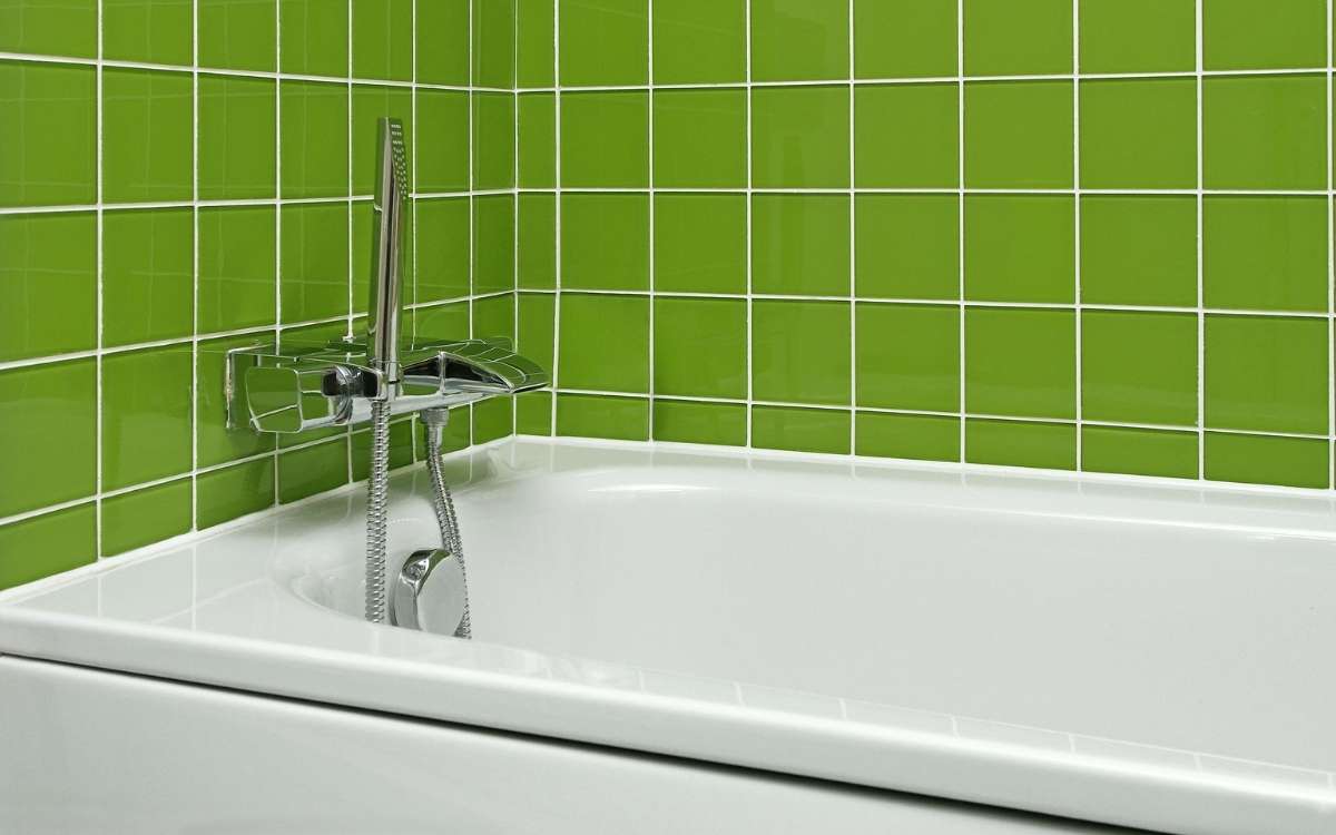Image of a bathtub beside the wall of green tiles