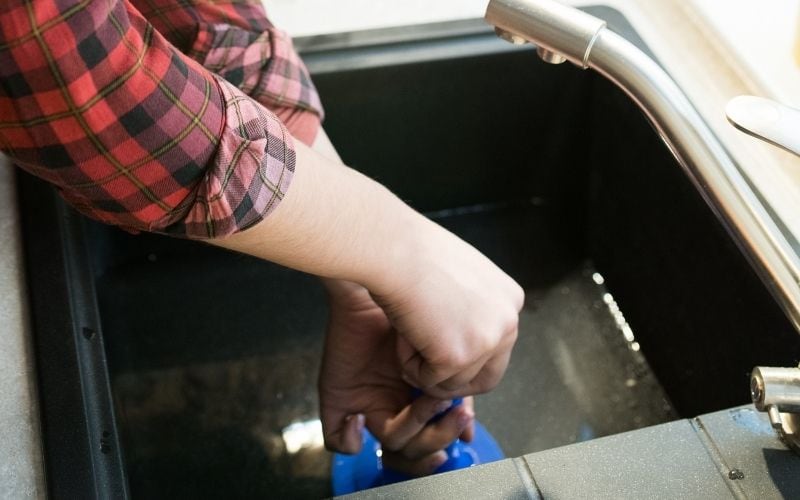 Photo of two hands holding a plunger over the sink