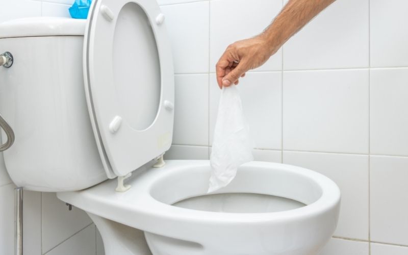 Image of a hand holding white tissue paper over a toilet bowl