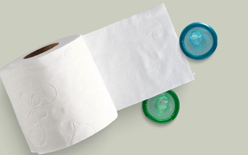 Photo of a roll of toilet paper beside the two pieces of condoms