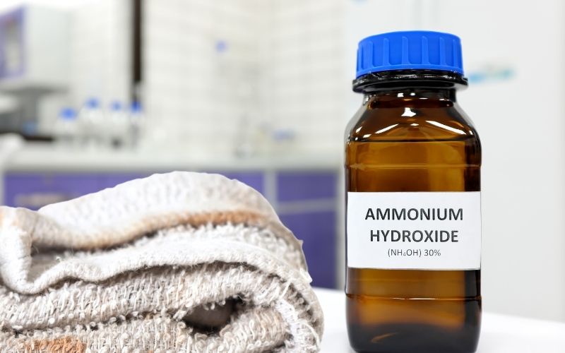 Image of a brown colored bottle of Ammonium Hydroxide to keep racoons poop on deck with a rag beside it