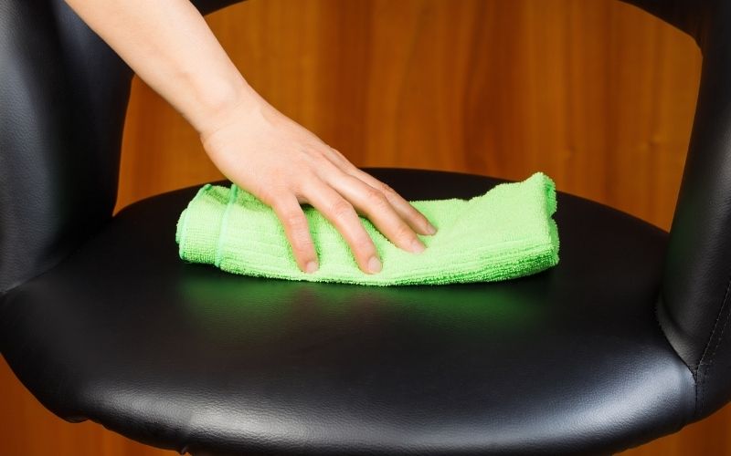 Image showing a hand wipng a leather chair using a green rag