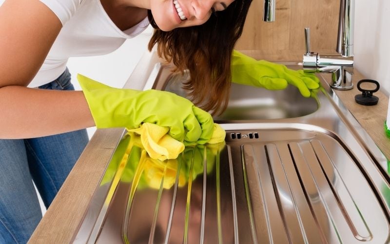 Image of a woman cleaning the stainless steel kitchen counter top