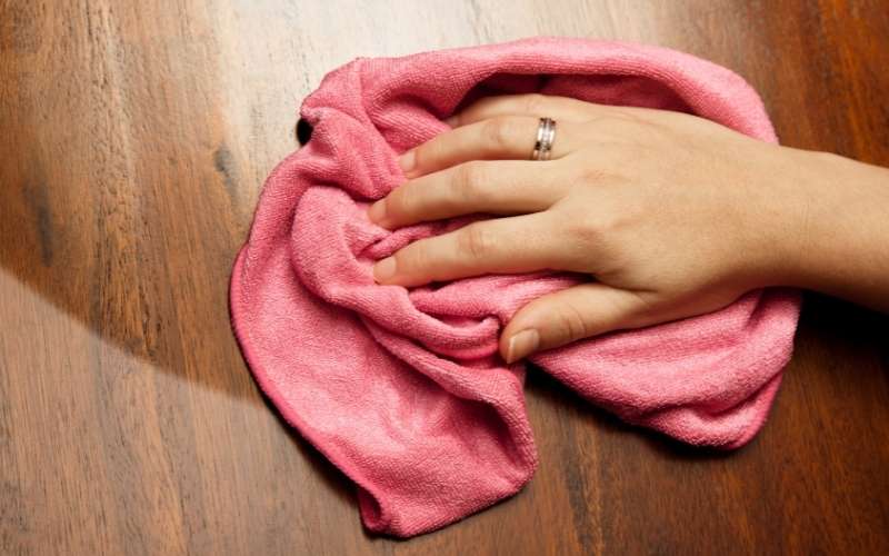 Photo of a hand holding a pink rag while wiping the floor