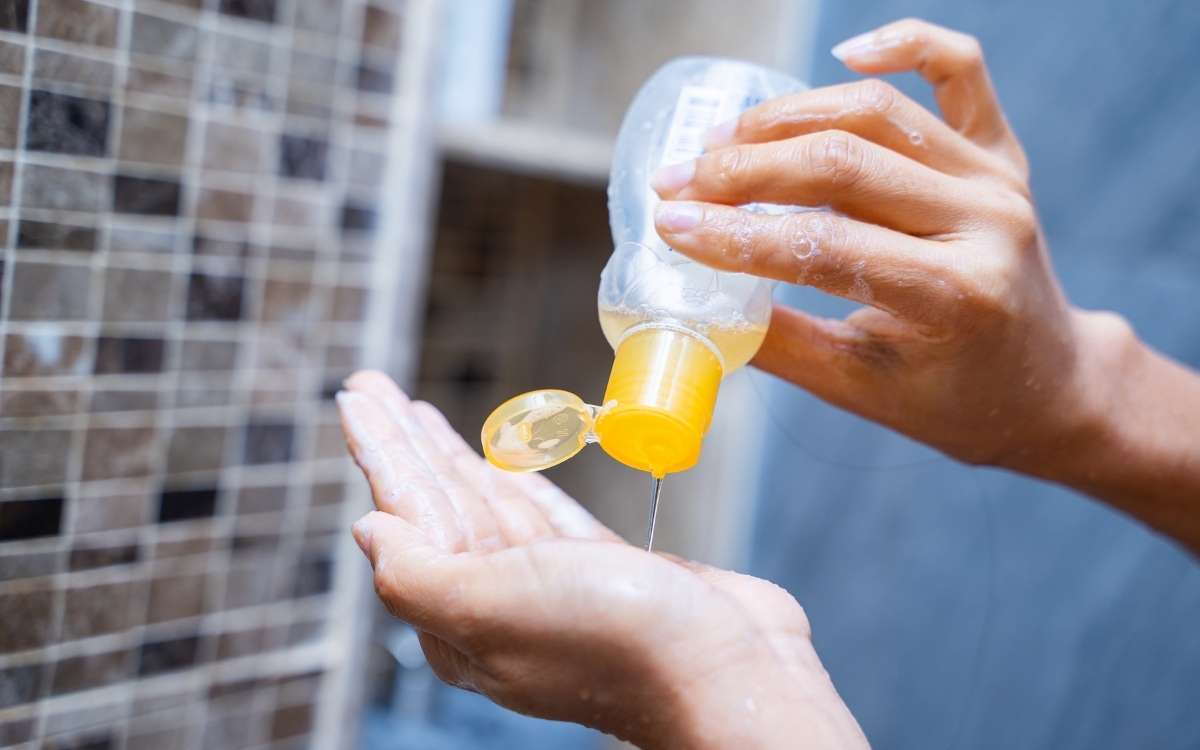 Photo of a hand holding a bottle with liquid and pouring it to the other hand