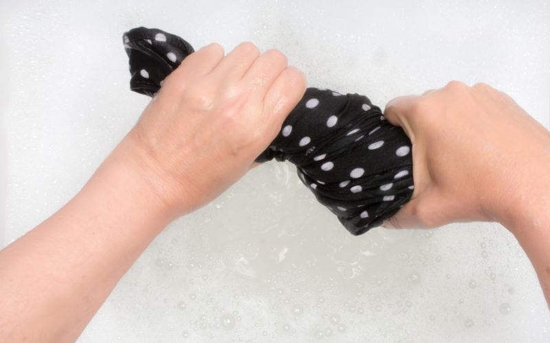 Photo of a pair of hands wringing a cloth to remove excess water