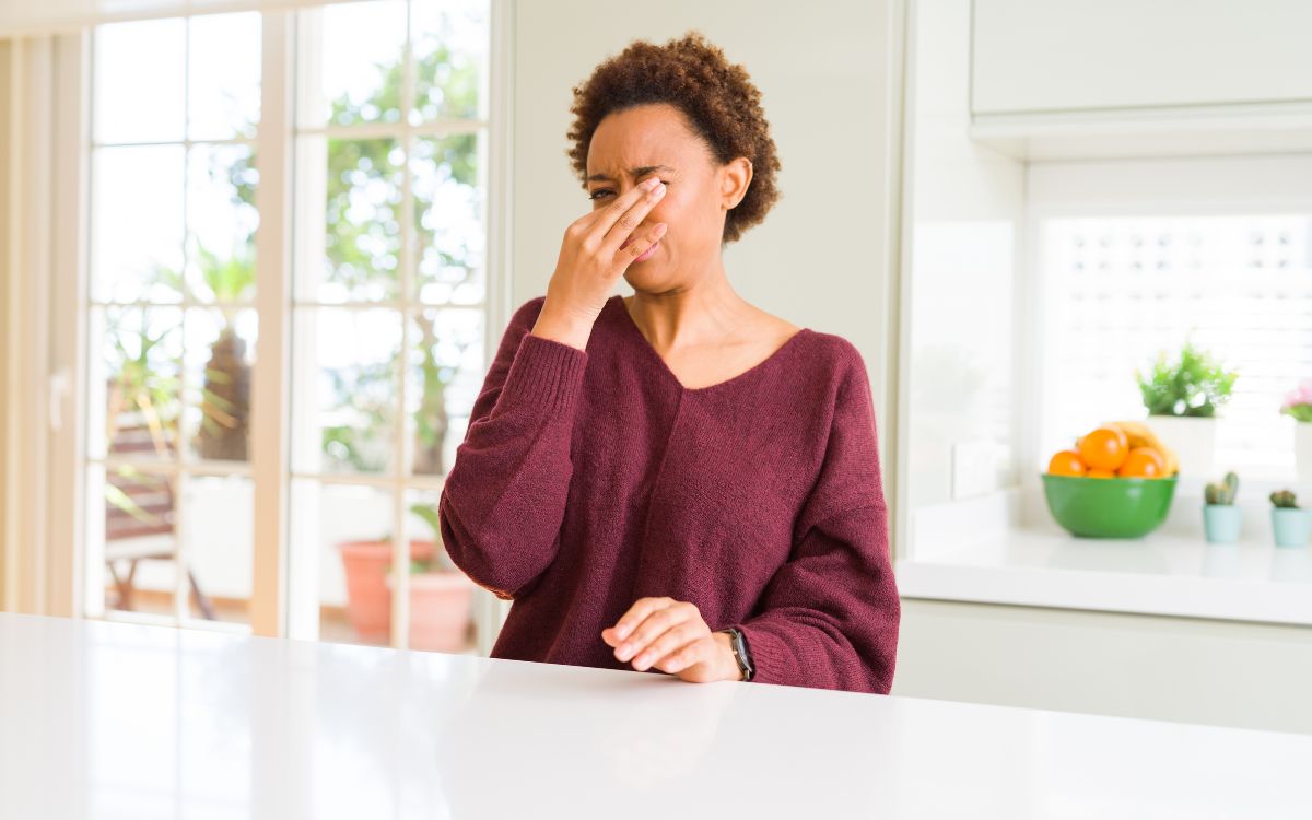 Photo of a woman pinching her nose as if the house smells like something bad.