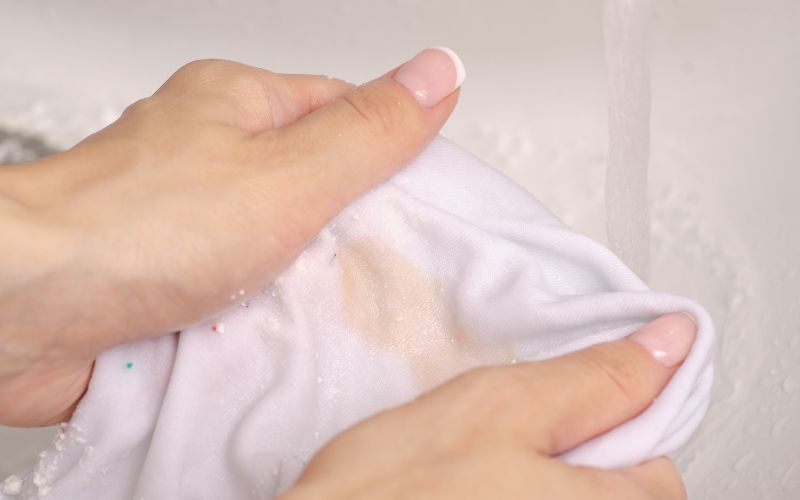 Pair of hands holding a towel with detergent trying to remove stain